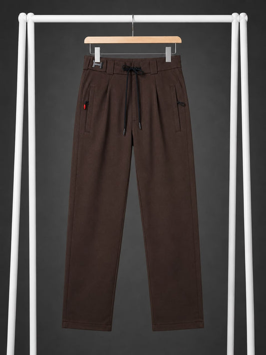A pair of dark brown wide-leg sweatpants hanging on a wooden hanger from a white clothing rack against a dark gray background.
